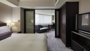 Een hotelkamer met een bed, televisie, bureau en stoel.
