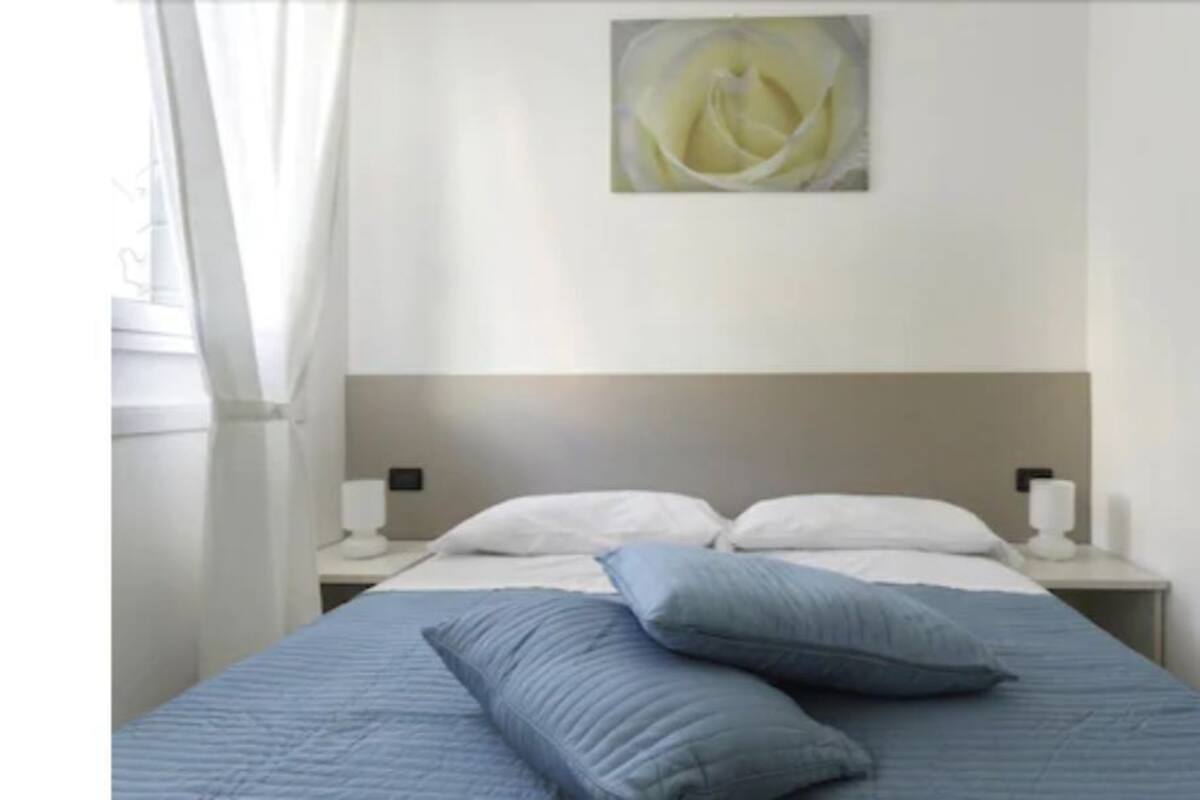 A bedroom with a bed, pillows, a nightstand, and a wall-mounted painting.