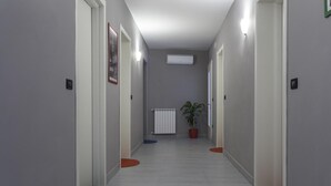 A hallway with white walls, a radiator, and a potted plant. - Easy Venice Room (Mestre)