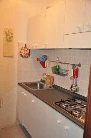 A kitchen with white cabinets, a stainless steel sink, and a gas stove. - At Home Bed and Breakfast (Lucca)