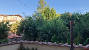 A rooftop terrace with a view of dense greenery and a building in the background. - At Home Bed and Breakfast (Lucca)