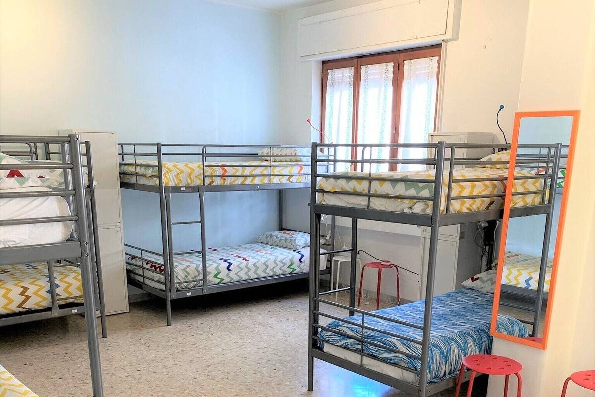 Un dormitorio con literas, un escritorio pequeño y una ventana con cortinas.