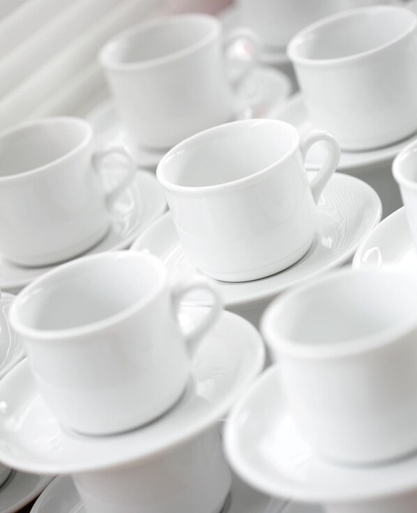 Una colección de tazas y platillos blancos dispuestos ordenadamente en una bandeja.