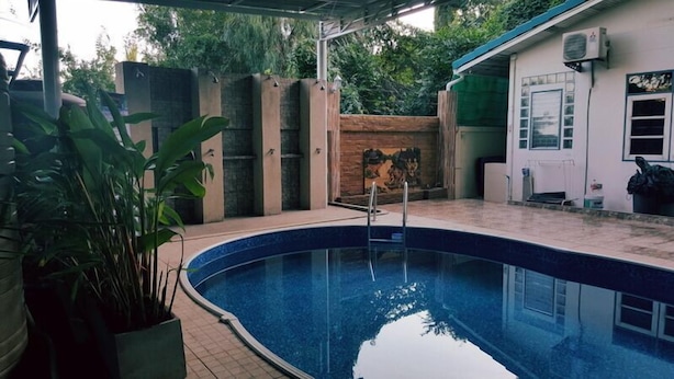 A swimming pool with a tiled deck, surrounded by a brick wall and a wooden fence. - Baan Suksabai Hua Hin (Hua Hin)