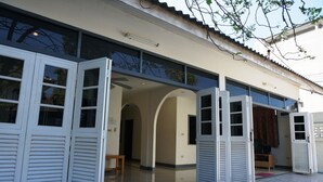 A building with multiple open doors leading to interior spaces, a tiled floor, and a clear sky. - Baan Suksabai Hua Hin (Hua Hin)