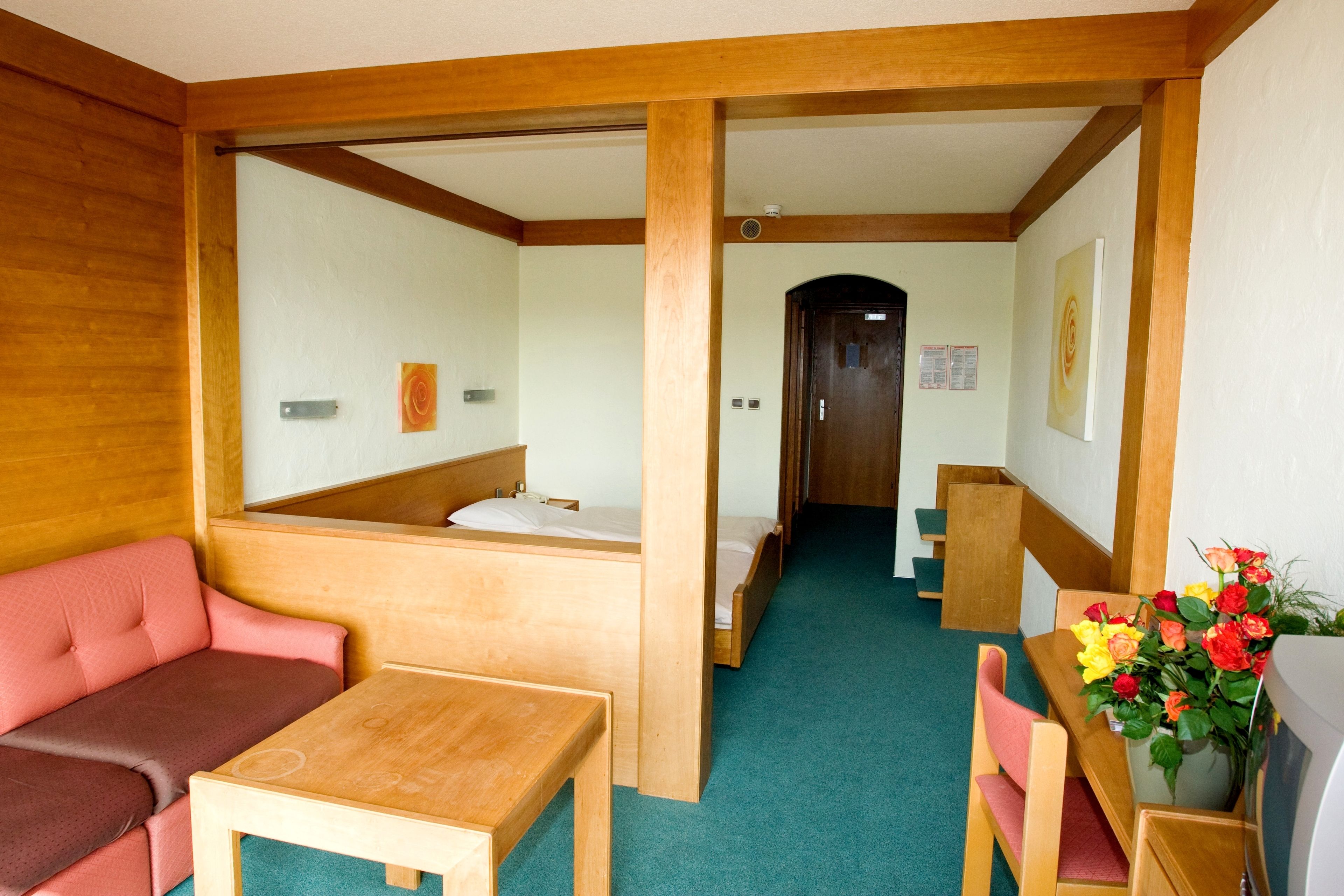 Una habitación de hotel con un banco de madera, una mesita, un sofá y una cama.