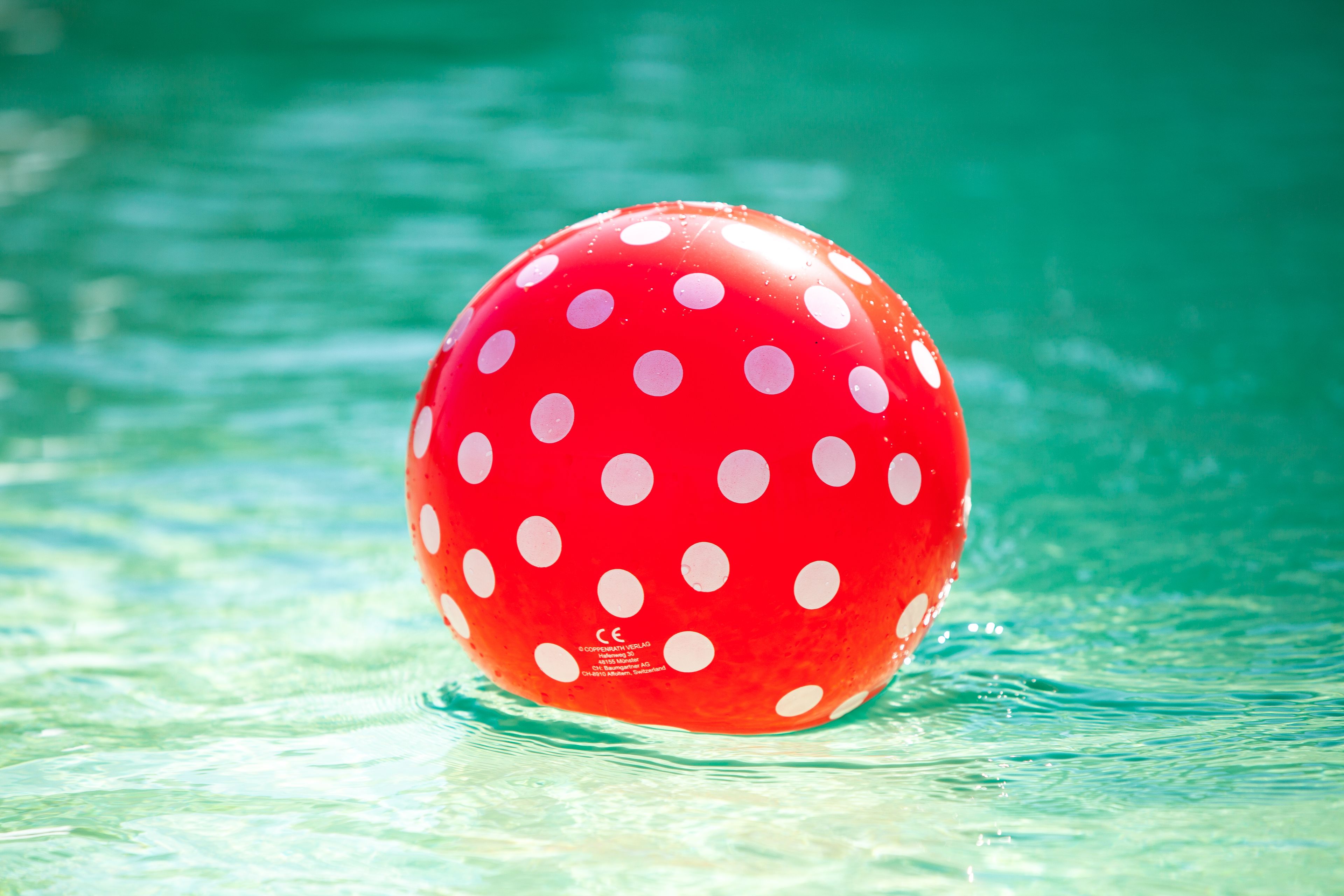 Una pelota roja con lunares flotando en el agua.