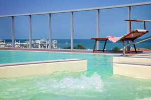 Una piscina con vista al mar y una silla con una toalla.