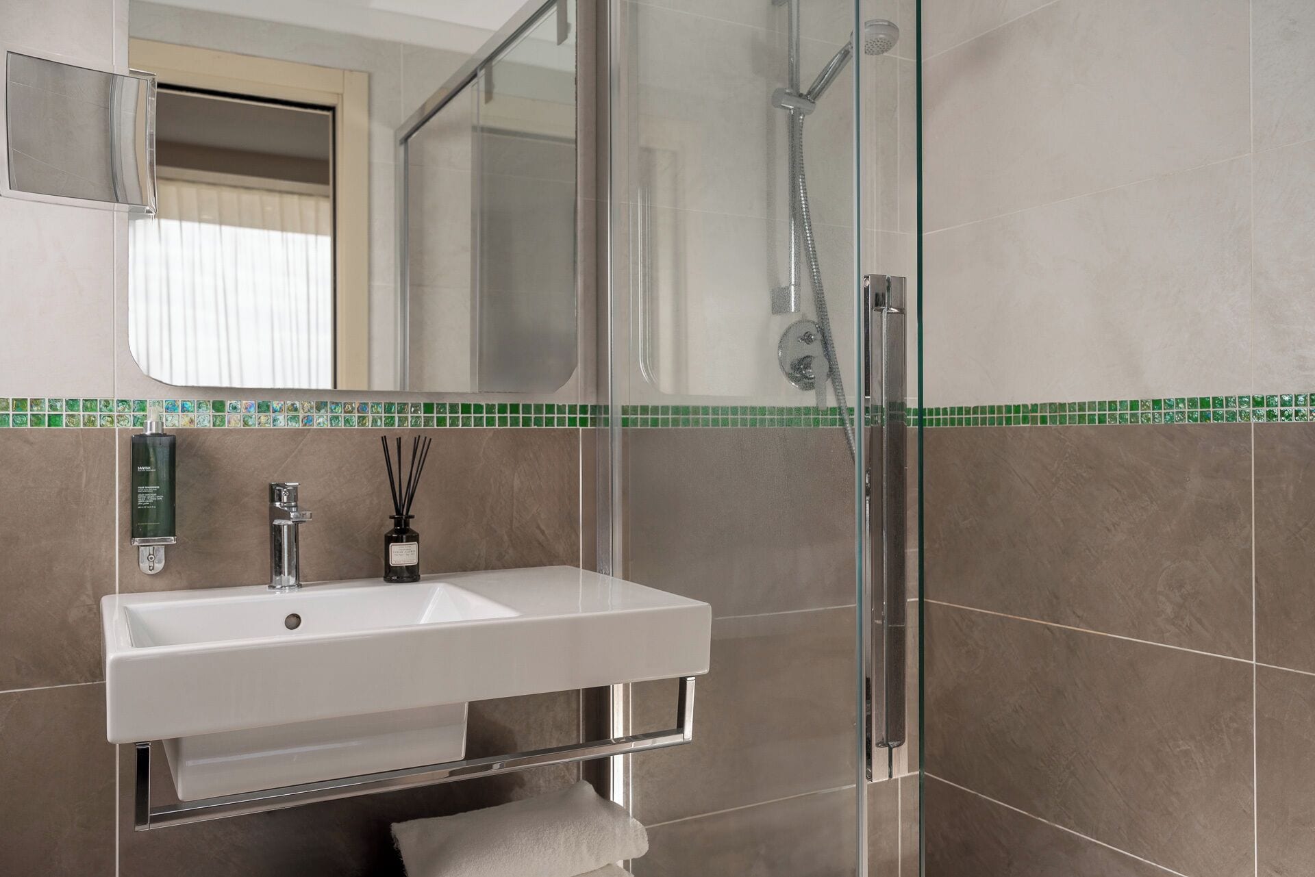 Une salle de bain avec une douche à parois de verre, un lavabo blanc et un miroir au-dessus.