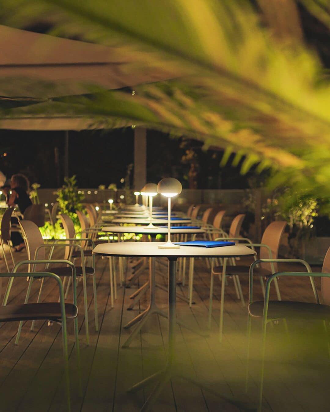 Un área de comedor al aire libre con mesas y sillas, bajo un toldo.