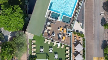 An aerial view of a hotel with a rooftop pool, outdoor seating area, and a landscaped garden.