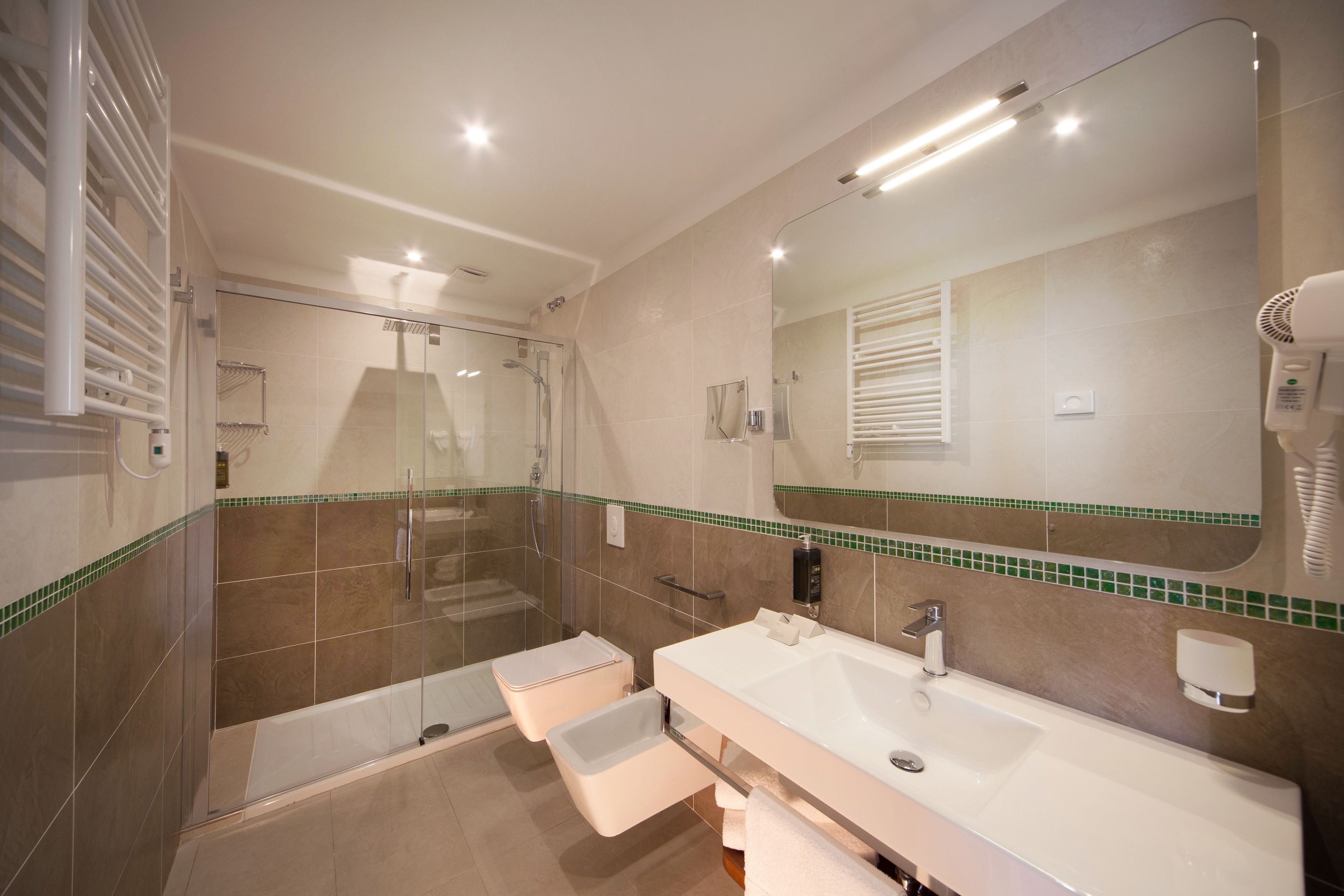 A modern bathroom with a glass-enclosed shower, a large mirror, and a vanity with a sink and towel rack.