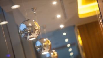 A series of spherical hanging lights with a clear reflection of the sky and buildings.