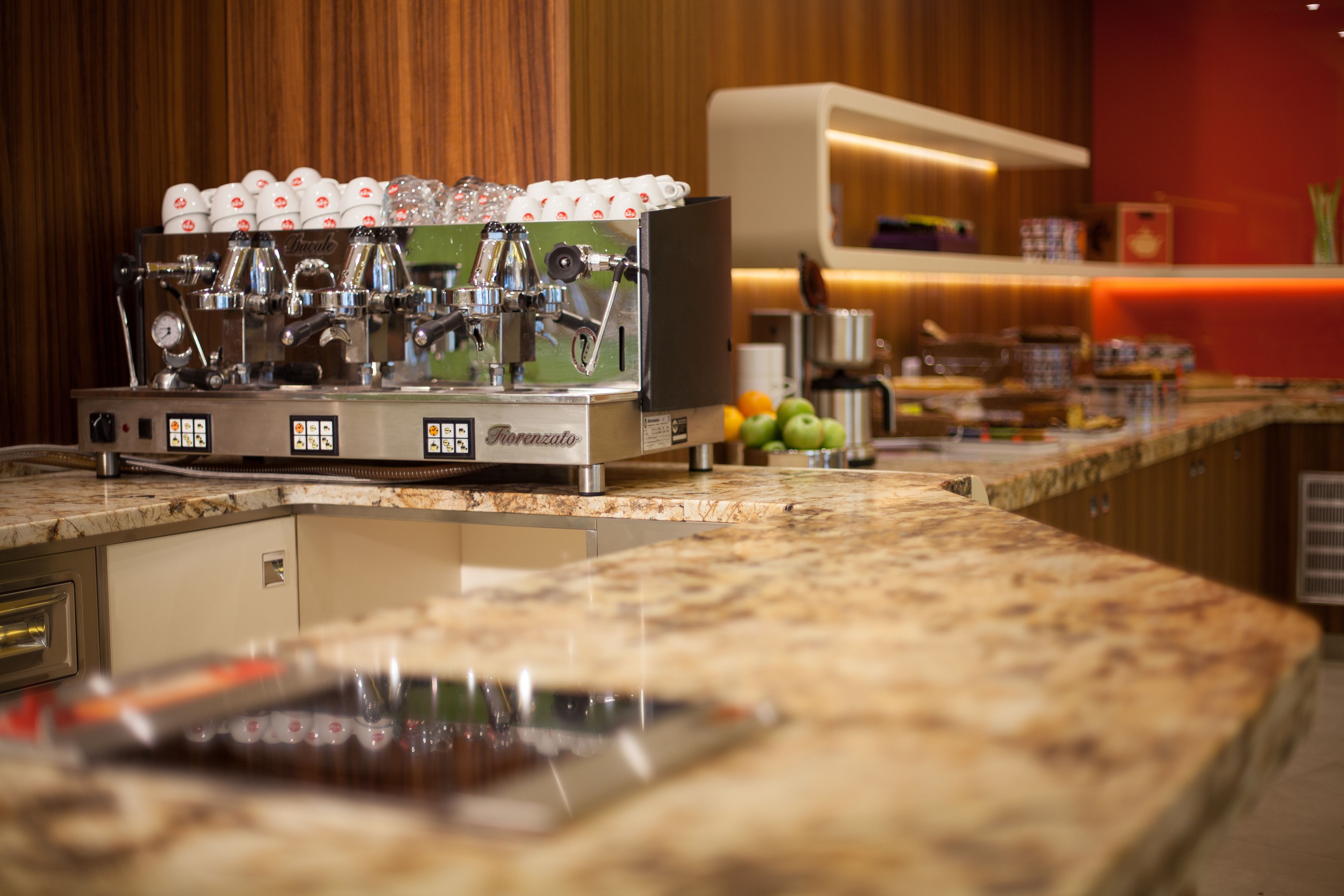 A coffee machine with multiple dispensers, a control panel, and a countertop with a marble surface.