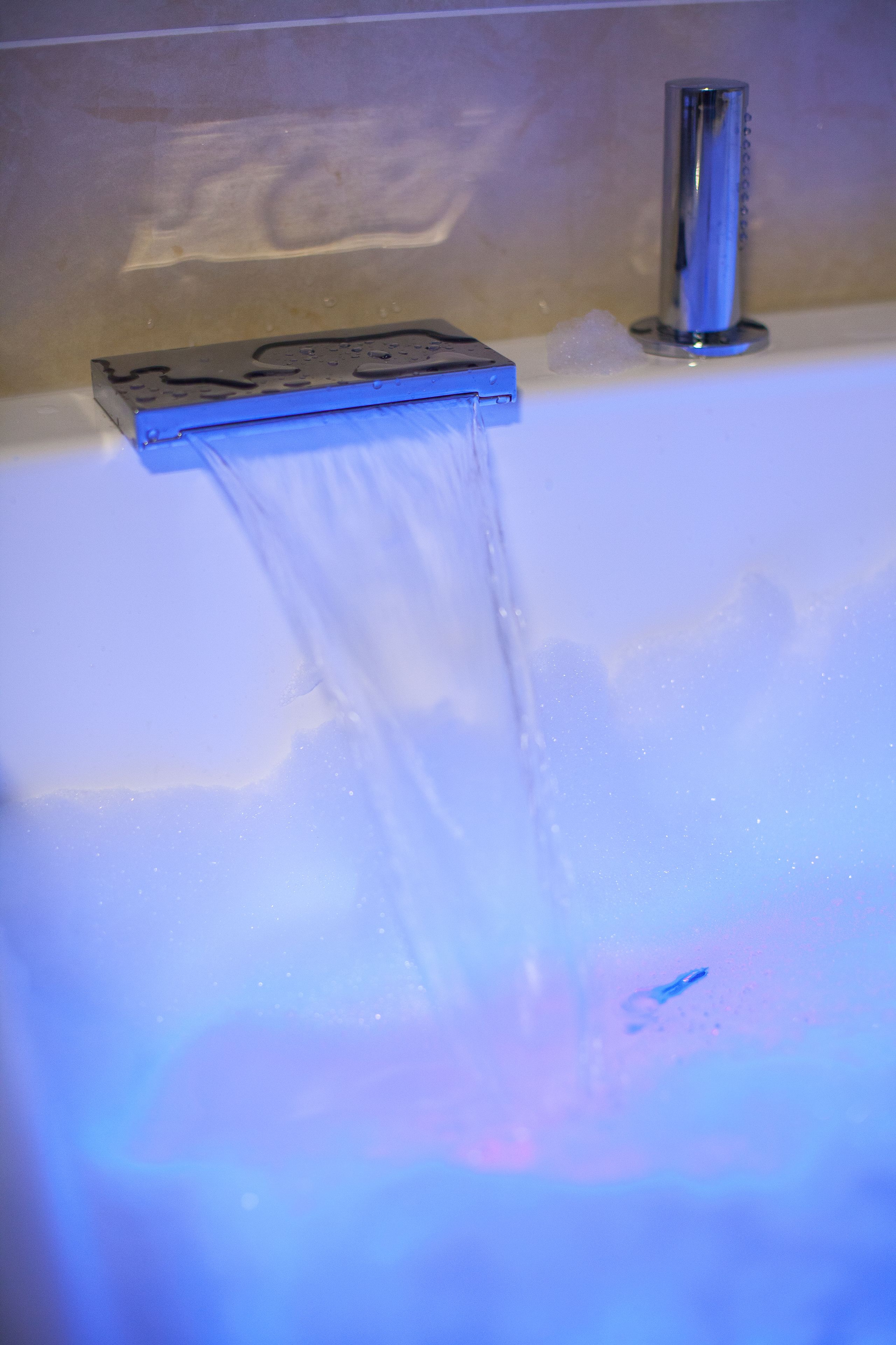 Una bañera con agua corriente, un grifo y un jabonera.
