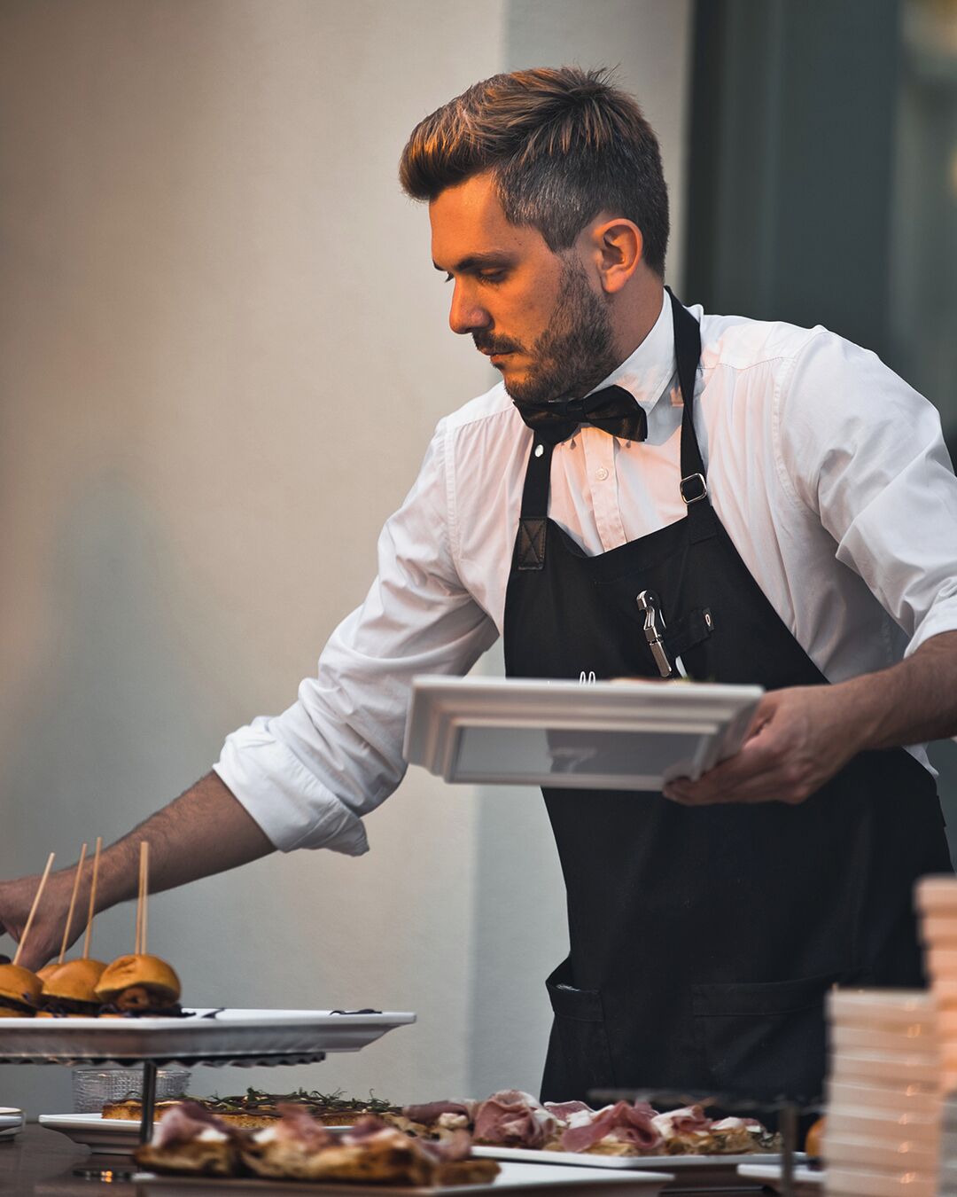 Una persona serve cibo a un buffet con diversi piatti su dei vassoi.