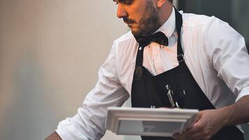 Una persona serve cibo a un buffet con diversi piatti su dei vassoi.