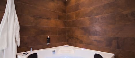 A modern bathroom with a large freestanding bathtub, wooden wall tiles, and recessed ceiling lighting.