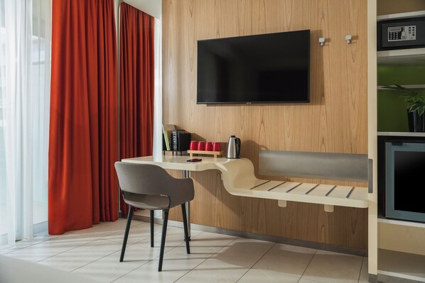 Una sala de estar moderna con un televisor montado en la pared, un sofá, una mesa de centro y un comedor con sillas.