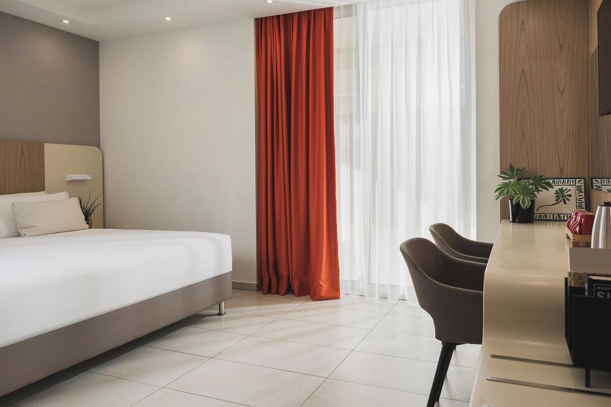 Une chambre d’hôtel moderne, équipée d’un lit, d’un bureau et d’une chaise.