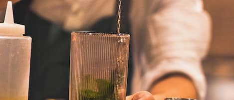 A bartender pouring a drink into a tall glass.