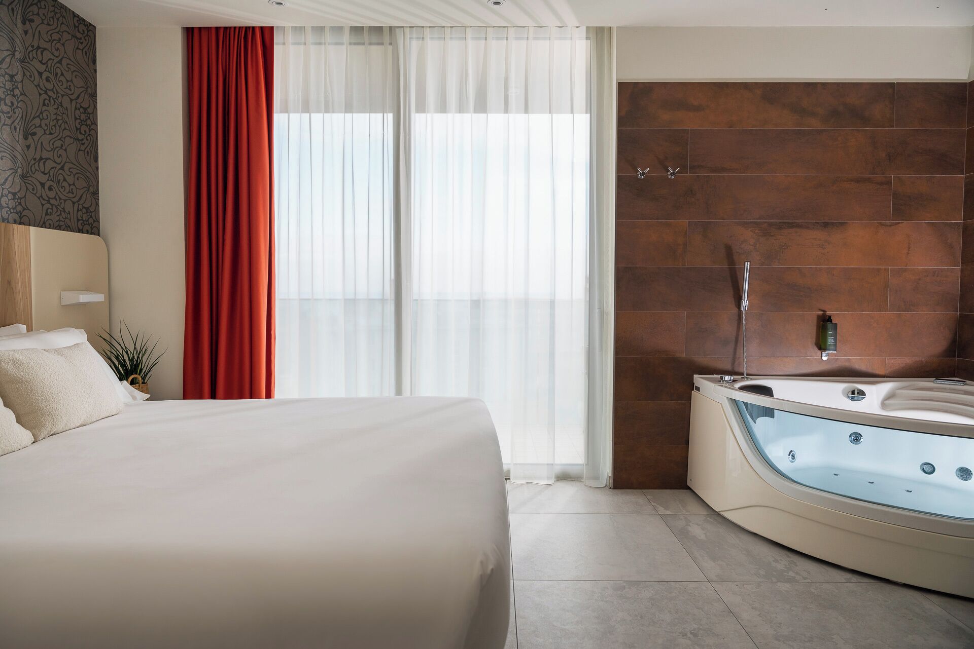 A modern hotel room with a large bed, a bathroom with a bathtub, and a view of the city.