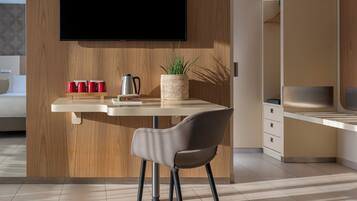 Una cucina moderna con una parete in legno a contrasto, una TV a schermo piatto montata sopra un piano di lavoro bianco e una sedia con cuscino grigio.