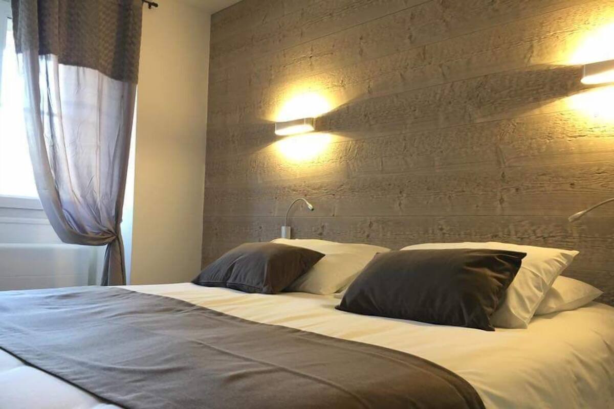 Una camera d'albergo con un letto grande, due comodini e un lampadario a parete.