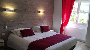 A bedroom with a wooden wall, a bed with white and red bedding, two bedside tables, and a window with red curtains.