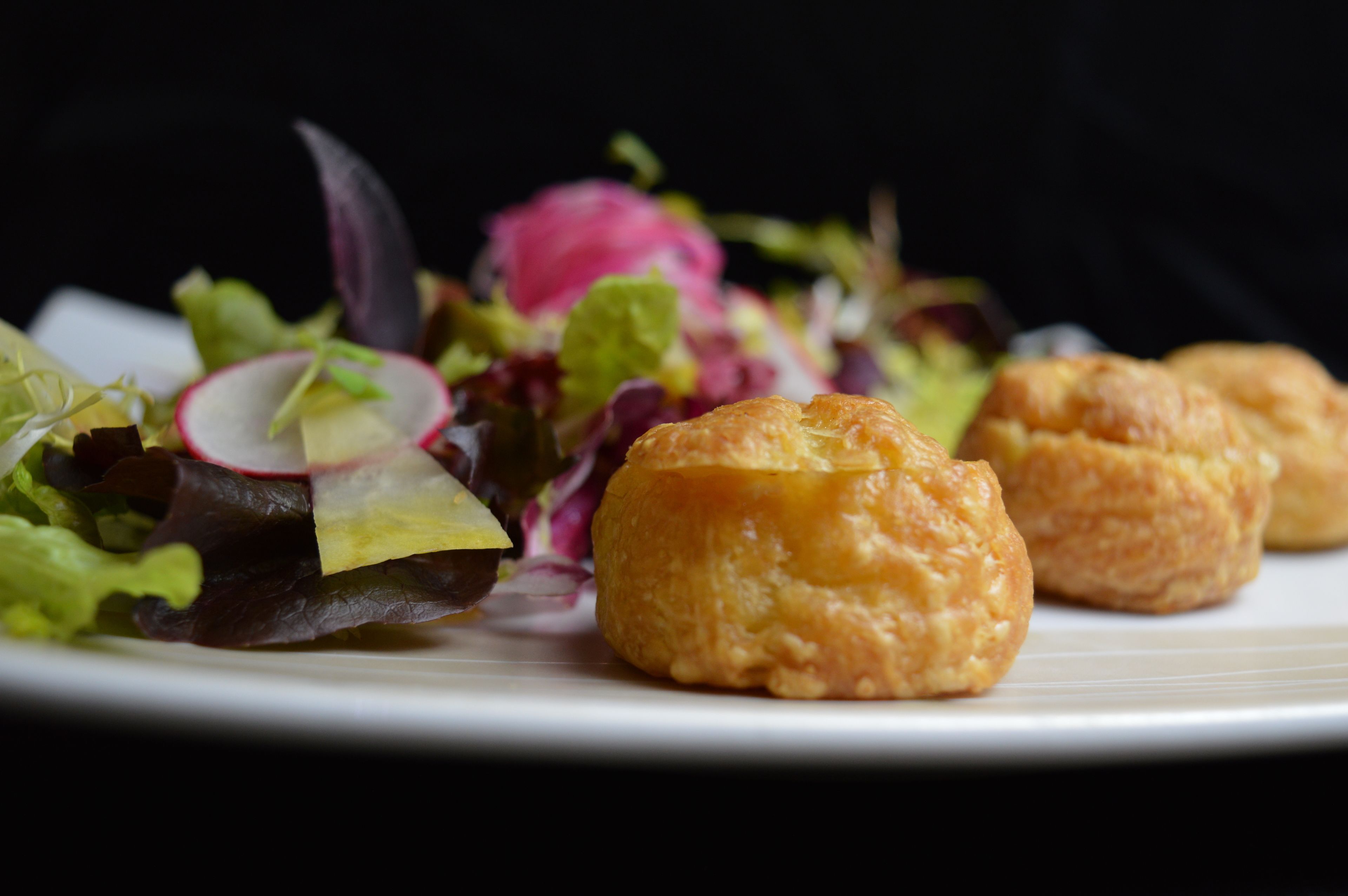 A plate with a salad and two pastries.