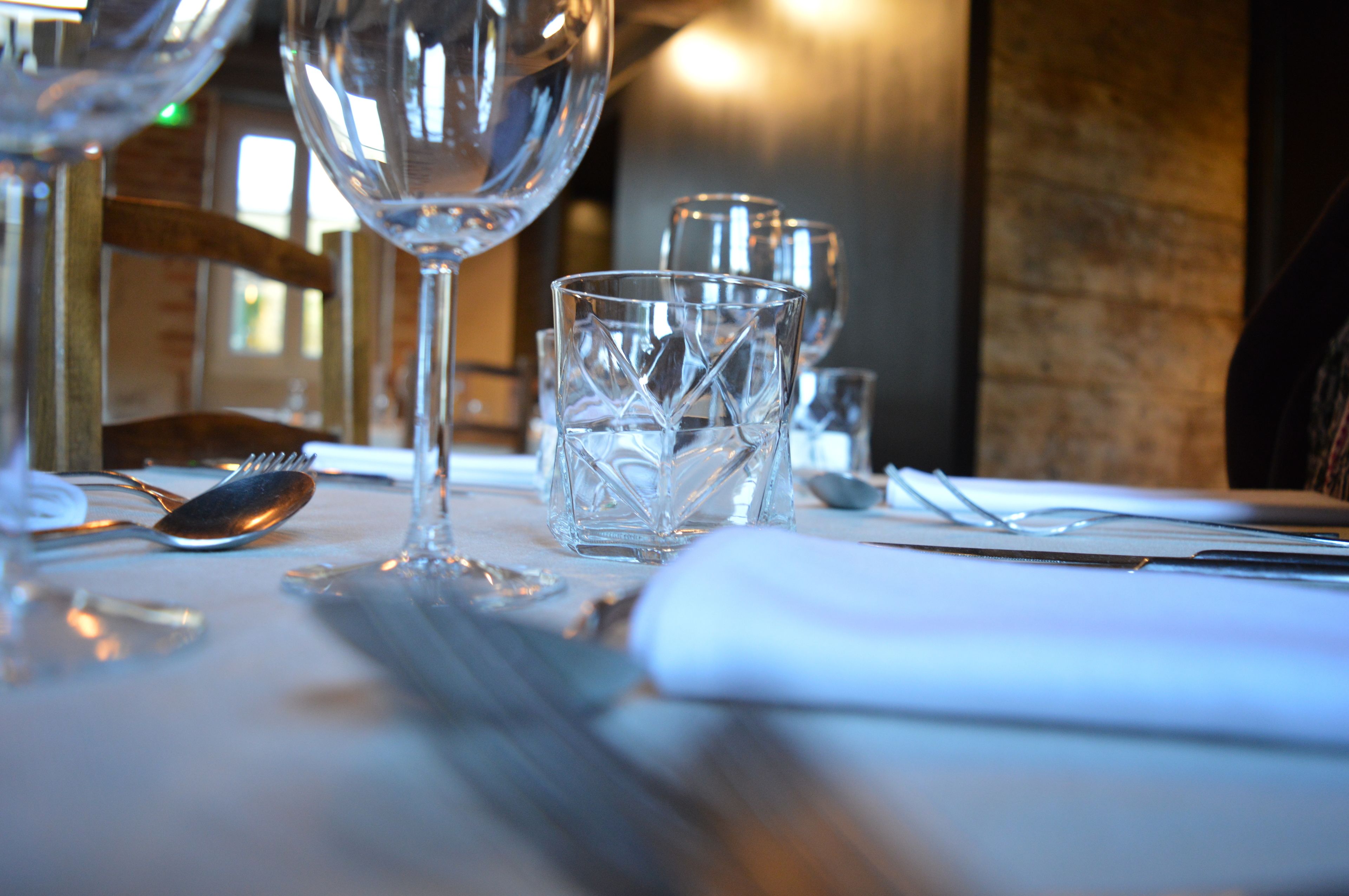 A dining table set with clear glassware and cutlery, indicating a formal dining setting.