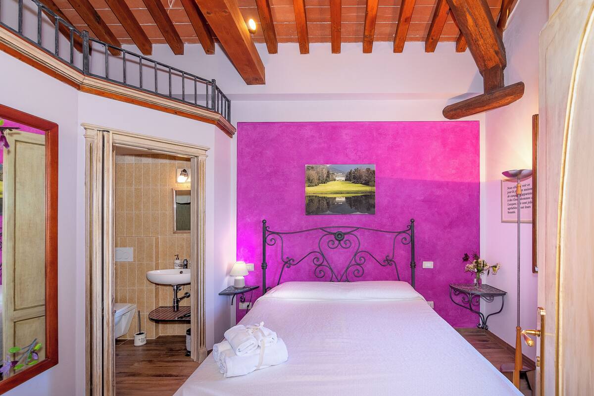 Quarto com cama, banheiro e varanda.