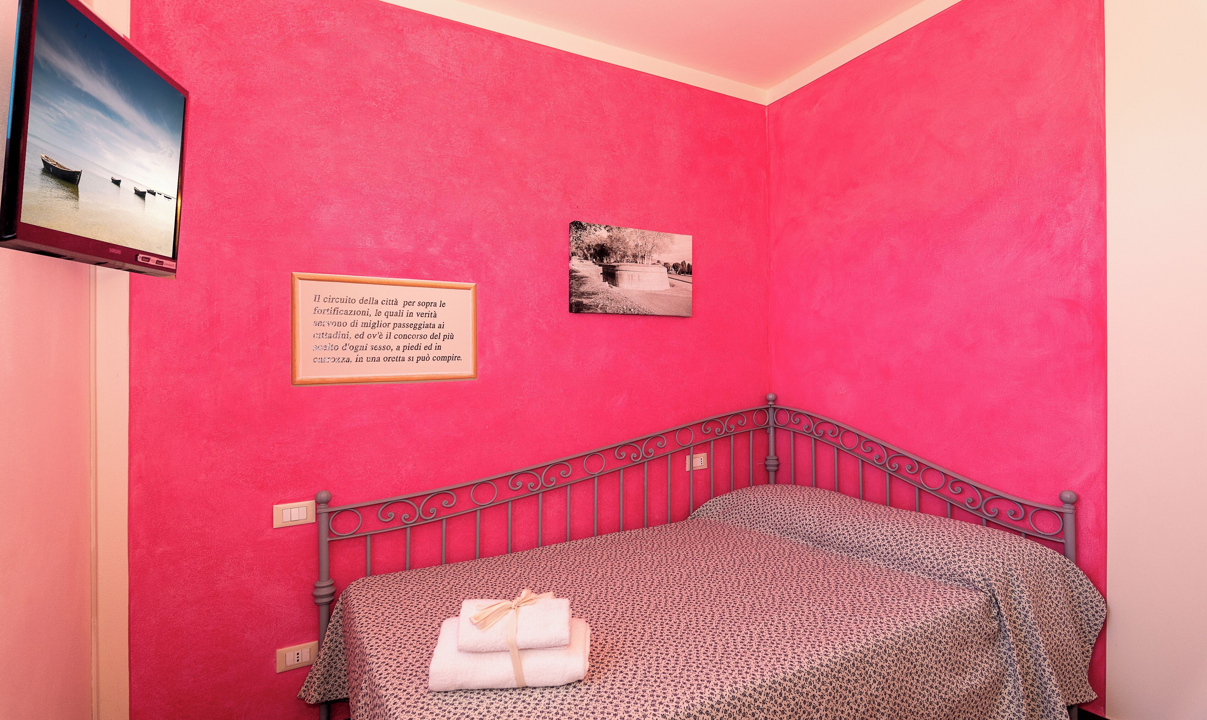 Une chambre avec un mur rose, un lit recouvert d’une couette à motifs léopard et deux tableaux encadrés.