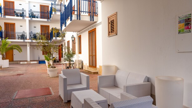 A spacious courtyard with wicker furniture, a staircase, and a balcony with blue railings. - Residence Marinella (San Vito Lo Capo)