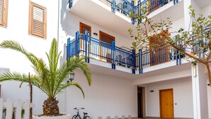 A white building with balconies, a palm tree, and a bicycle. - Residence Marinella (San Vito Lo Capo)