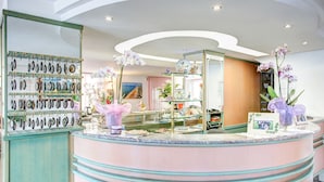 Un espace d’accueil avec un comptoir incurvé, un présentoir de boucles d’oreilles et des orchidées.