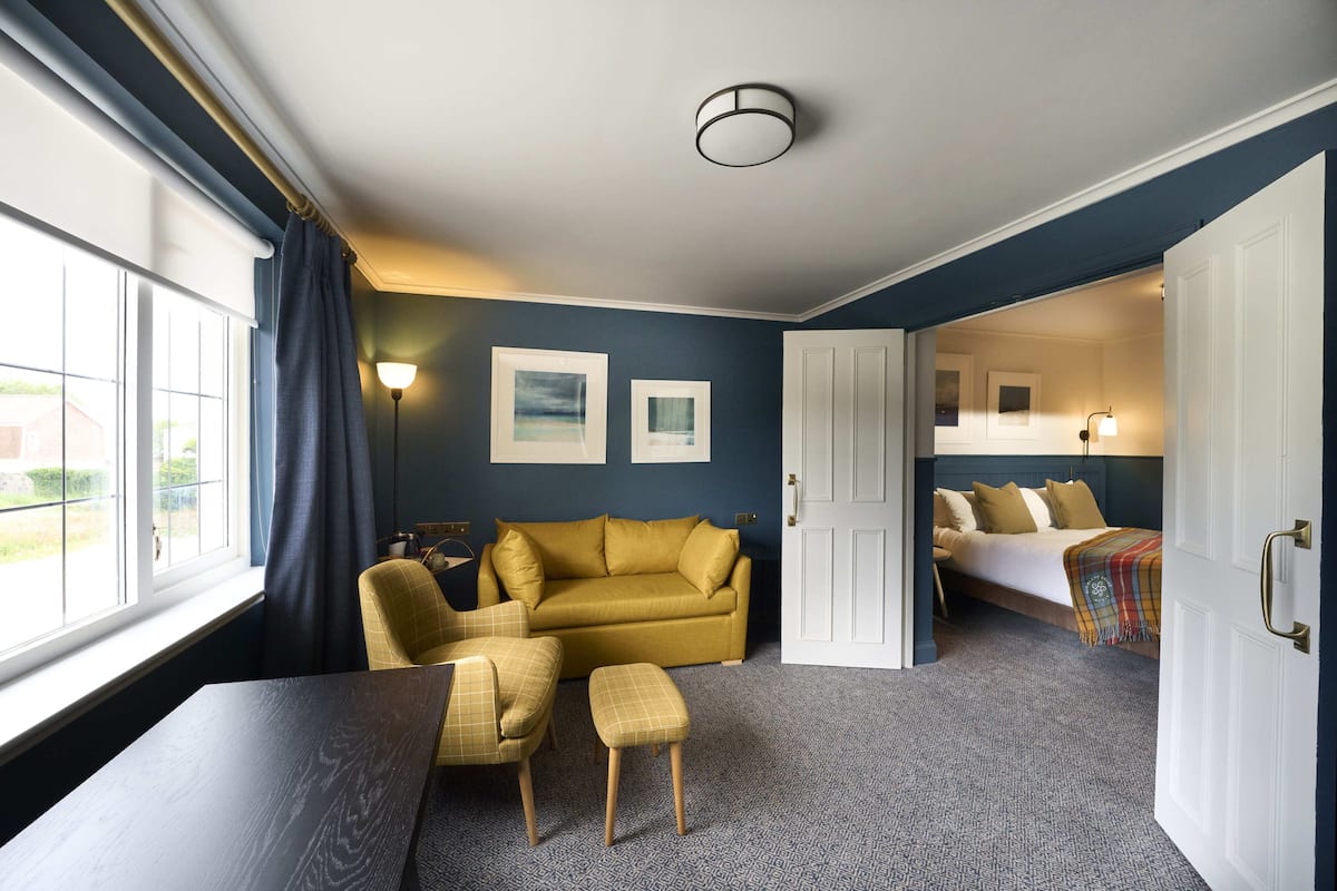 A room with a sofa, a bed, a table, and a chair.