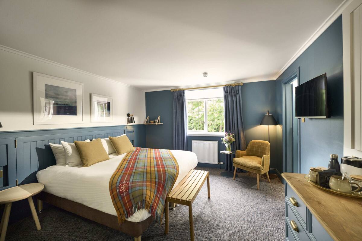 Ein Schlafzimmer mit Bett, Nachttisch, Stuhl und Fernseher an der Wand.