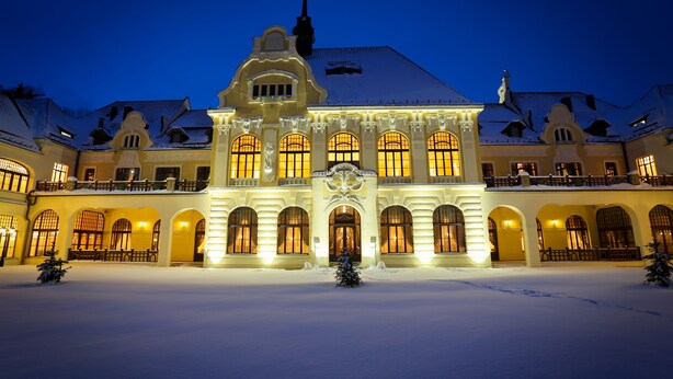 A grand, illuminated building with arched windows and a snow-covered courtyard. - Rubezahl Marienbad Luxury Historical Castle Hotel & Golf - Castle Hotel Collection (Marianske Lazne)