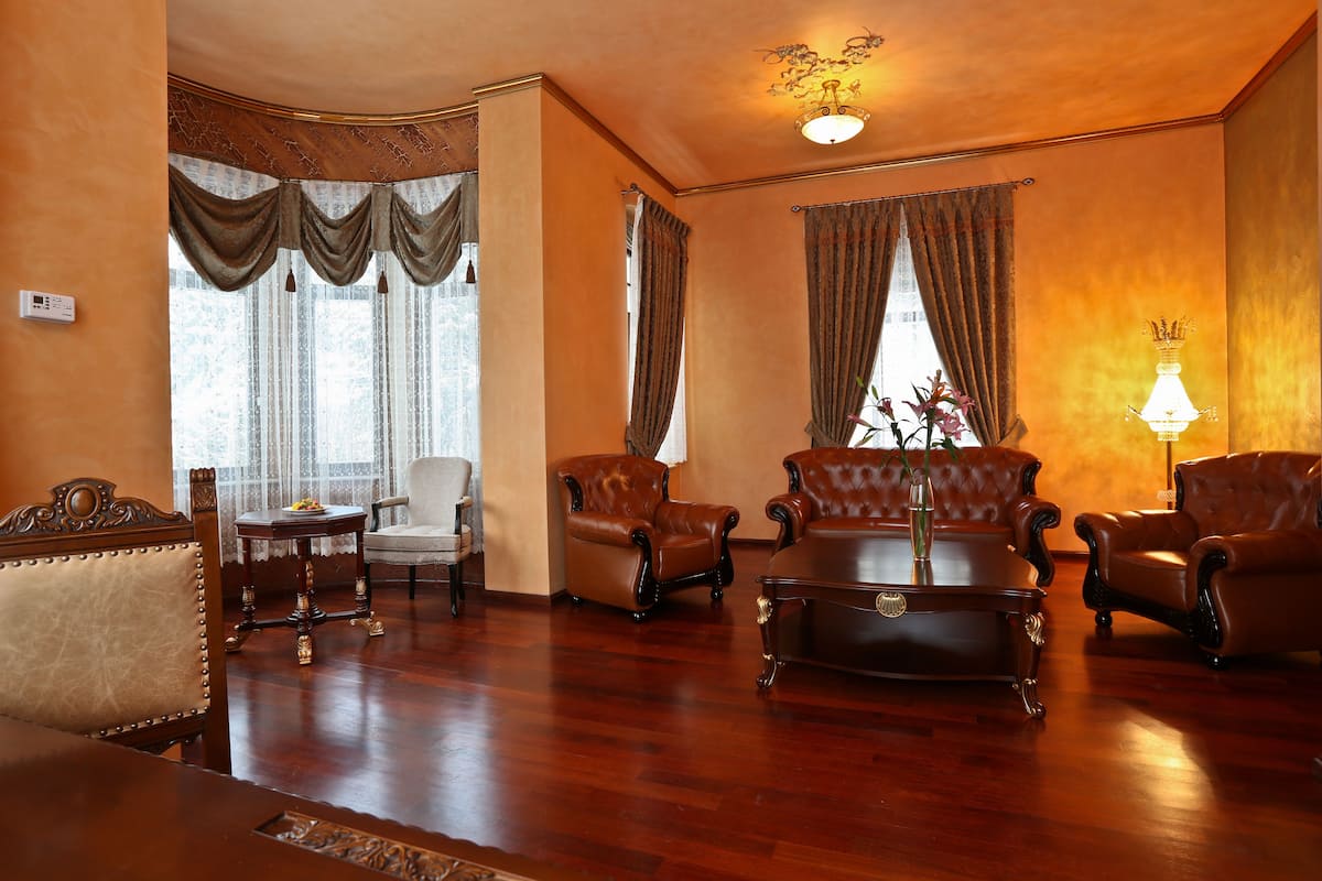 A traditional room with a wooden floor, leather armchairs, a sofa, and a table with a vase.