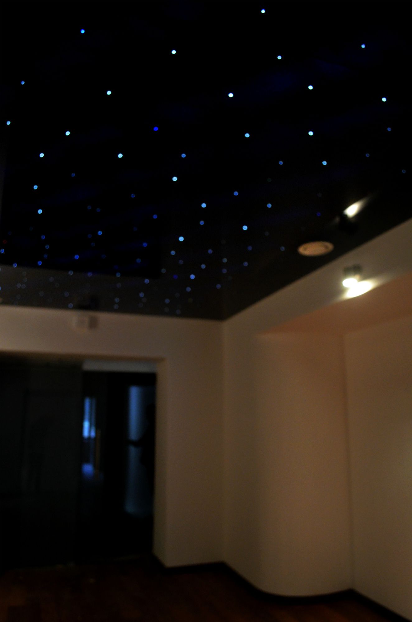 A room with a sloped ceiling and a visible door leading to another area.
