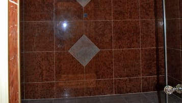 Bathroom features a unique tile design with a central diamond-shaped accent and a bench with a glass top.