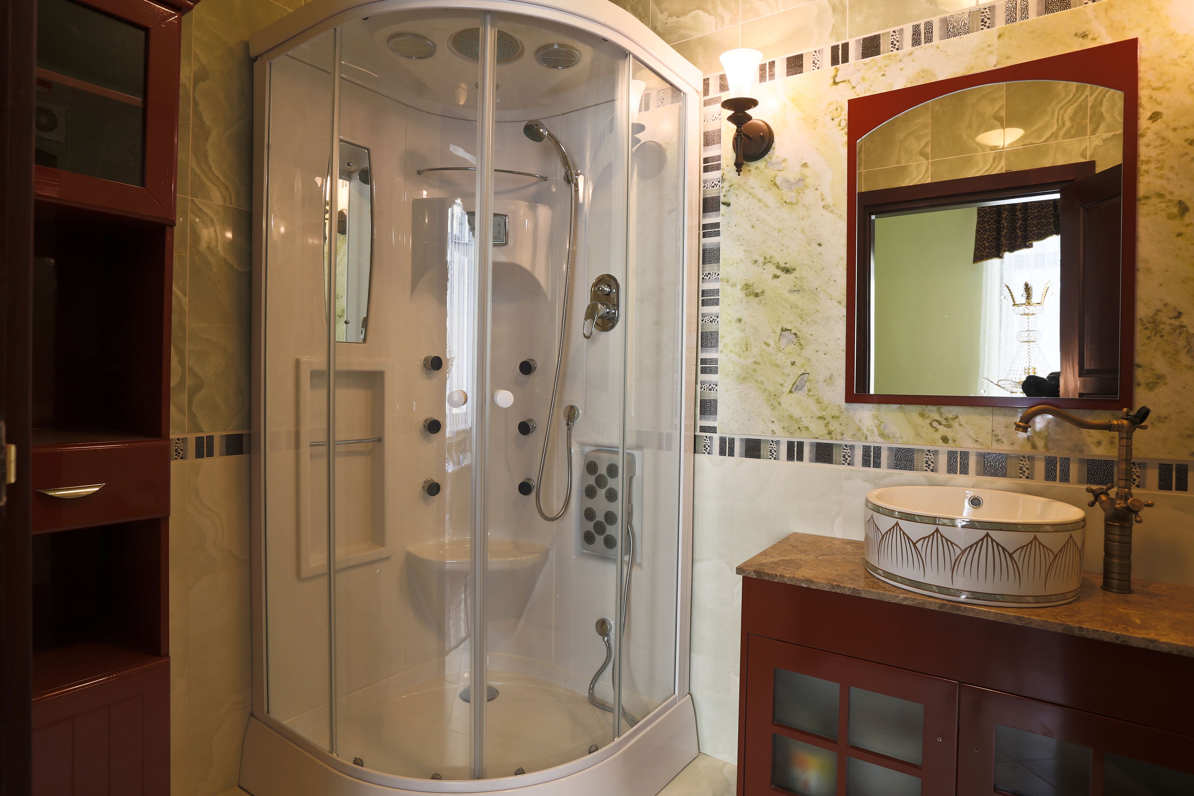 A bathroom with a glass-enclosed shower, a sink with a decorative basin, and a mirror with a crown design above it.