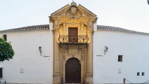 A historic building with a central entrance, two smaller doors on either side, and a decorative balcony. - Arunda I (Ronda)