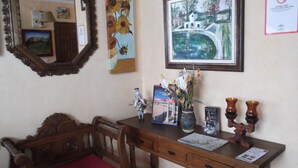 A wooden desk with a red cushion, a framed painting of a landscape, and a mirror. - Arunda I (Ronda)