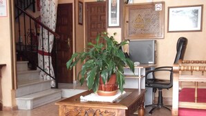 A wooden table with a potted plant, a chair, and a staircase in the background. - Arunda I (Ronda)