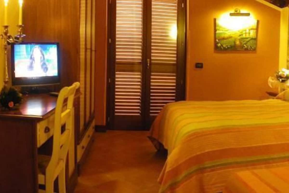 Ein Hotelzimmer mit zwei Betten, einem Fernseher, einem Schreibtisch und einer Steinwand.