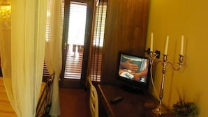 Een gezellige slaapkamer met een bed, een televisie en een kandelaar.