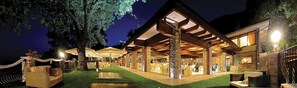 An outdoor patio area with seating and tables, a pool, and a covered walkway.