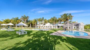 A pool area with lounge chairs and umbrellas, surrounded by palm trees and a building labeled "Reception".